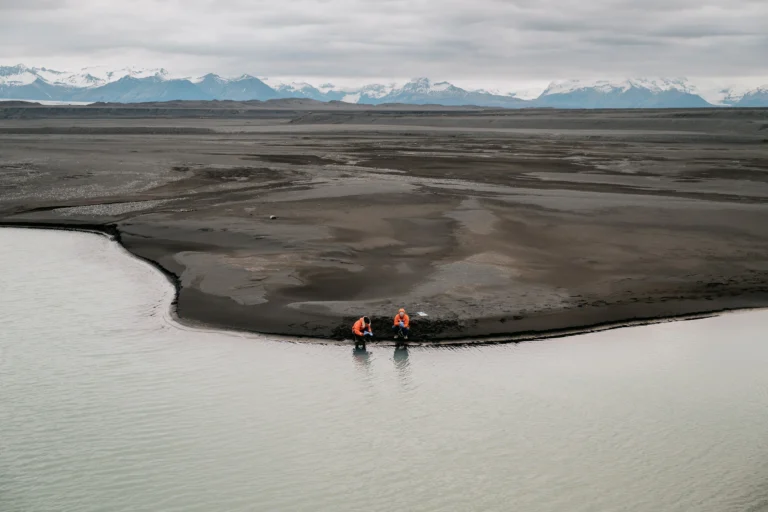 Researchers collecting water samples with a mountain range in the background.
