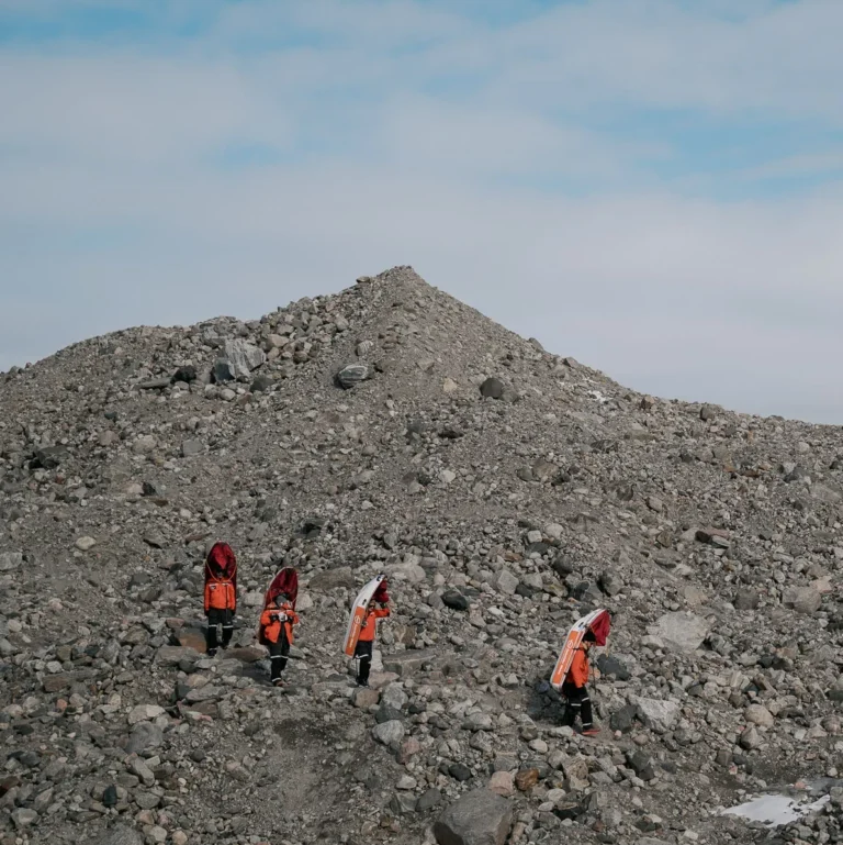 people carrying sleds on their backs over stones