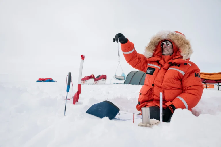 Scientist sitting in snow, measuring snow density