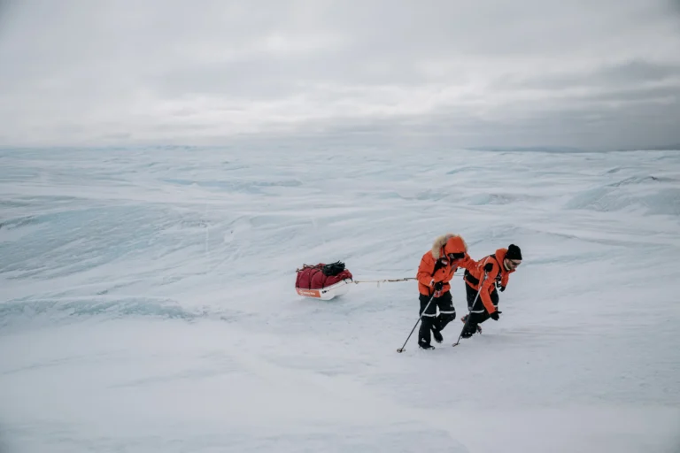 two scientists pulling a supply sled across a glacier
