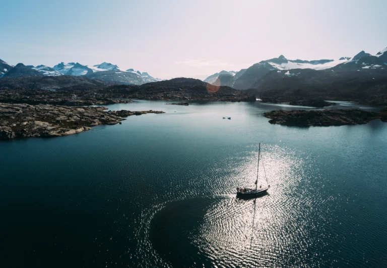 Sailing boat In a fjord. snow covered mountains in the background.