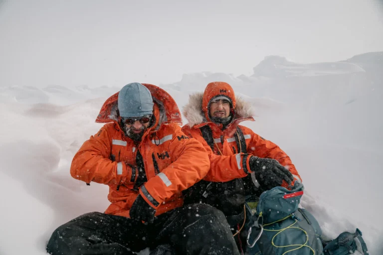 two men infront of a snow wall