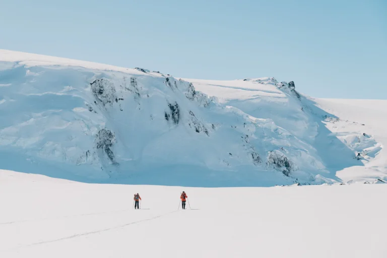 Two men skiing towards a mountain covered with snow
